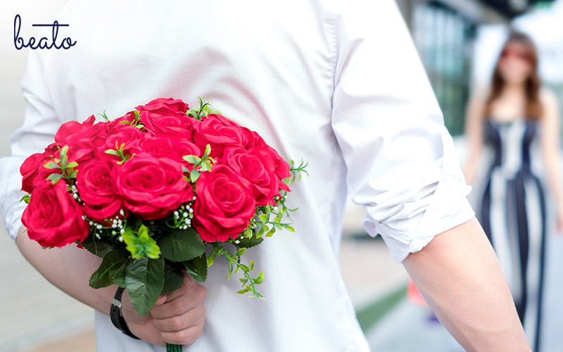 man hiding a bouquet of roses behind his back